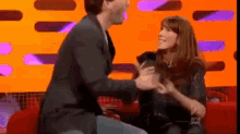 a man and a woman are sitting on a red couch .