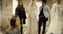 a woman in a blue dress is sitting in front of a man in a cowboy hat and a bride in a white dress