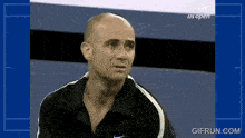 a man in a black nike shirt is sitting in front of a screen that says us open