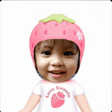 a baby wearing a strawberry helmet and a love sweets shirt