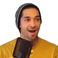 a man wearing a yellow shirt and a black beanie is singing into a microphone