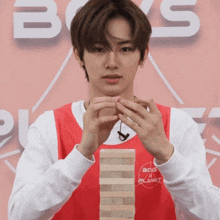 a boy in a boys ii planet shirt holds a stack of blocks
