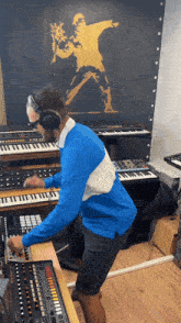a man wearing headphones is playing a keyboard in front of a wall with a picture of a man holding flowers