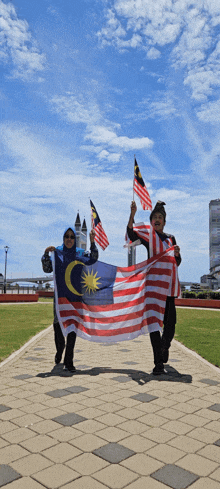 a man and a woman holding a large malaysian flag on a sidewalk