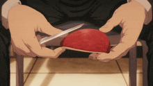 a person cutting a red apple with a pair of scissors