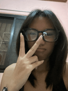 a girl wearing glasses is giving the peace sign
