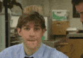 a man in a blue shirt and tie making a face