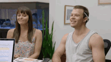 a man and a woman are sitting in front of a computer and smiling
