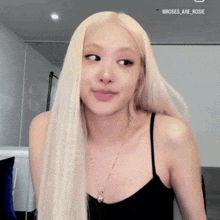 a woman with long blonde hair is wearing a black tank top and a necklace