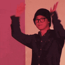 a man wearing glasses and a hat covering his face with his hands