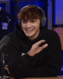 a man wearing headphones and a black hoodie that says supreme on it