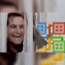 a man is smiling while looking out of a hole in the wall .