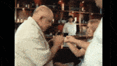a man and a girl are holding hands in front of a bar with bottles on the shelves