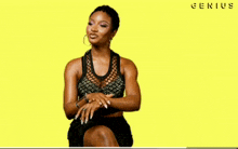 a woman is sitting in front of a yellow background and the word genius is on the bottom right