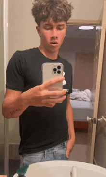 a young man is taking a picture of himself in the bathroom mirror .