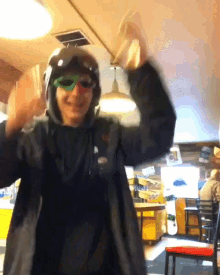 a man wearing a helmet and green sunglasses is dancing in a restaurant