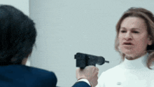 a man is pointing a gun at a woman in a white sweater