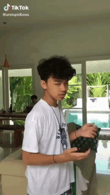 a young man in a white shirt is holding a cell phone in a living room ..