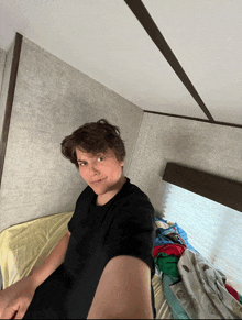 a young man in a black shirt is taking a selfie in a bedroom