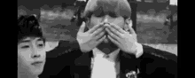 a man in a suit is covering his mouth with his hands .