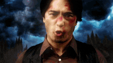 a man with blood on his face is wearing a brown shirt and black vest