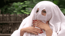 a woman with red nails is wrapped in a white ghost costume