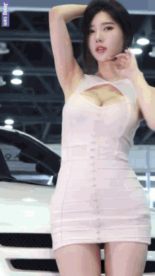 a woman in a white dress is standing in front of a white car with a purple sticker that says jung ram