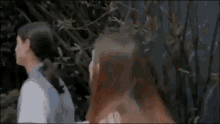 two women are standing next to each other in front of a tree .