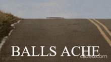 a man is standing on the side of a road with the words " balls ache " written on it