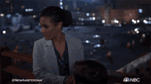 a woman is standing on a balcony with a nbc logo in the corner