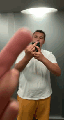 a man in a white shirt and yellow shorts is taking a picture of himself