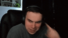 a man wearing headphones is giving a thumbs up sign while sitting in a chair .