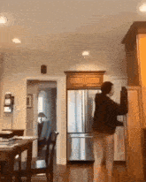 a woman is standing in a kitchen reaching into a refrigerator