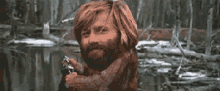 a man with a beard and long hair is holding a gun .