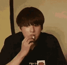 a young man is eating a piece of food while wearing a black shirt .