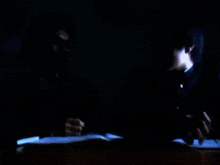 a man in a suit is reading a book in a dark room