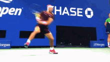 a tennis player swings a racket in front of a chase sign