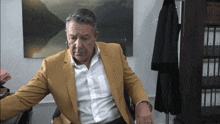 a man in a yellow jacket and white shirt sits in an office
