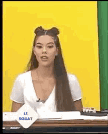 a woman with long hair is sitting at a table in front of a yellow wall .