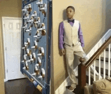 a young boy in a suit and bow tie is standing on a staircase next to a wall .