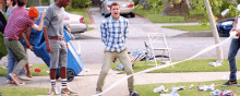 a man is standing on a sidewalk with a roll of toilet paper .