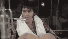 elvis presley is playing a guitar in front of a microphone .
