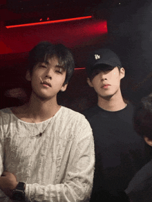 two young men standing next to each other with one wearing a la hat