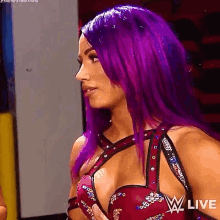 a woman with purple hair is wearing a red and black dress and looking at the camera .