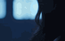 a woman is sitting in a dark room with a blue light behind her .