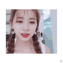 a close up of a woman wearing earrings and a white tank top