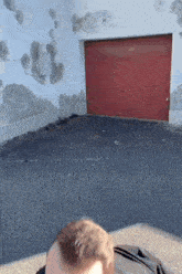 a man is laying in front of a red garage door