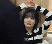 a woman in a black and white striped sweater is stretching her arms