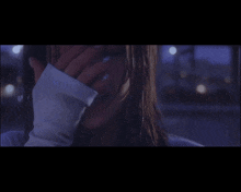 a close up of a woman covering her face with her sleeve