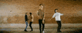 a group of men are dancing in front of a brick wall